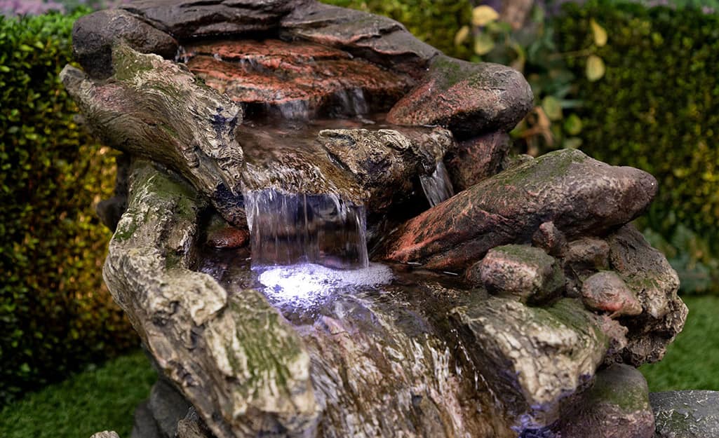 An outdoor water fountain with a lit waterfall feature. An outdoor water fountain with a lit waterfall feature.