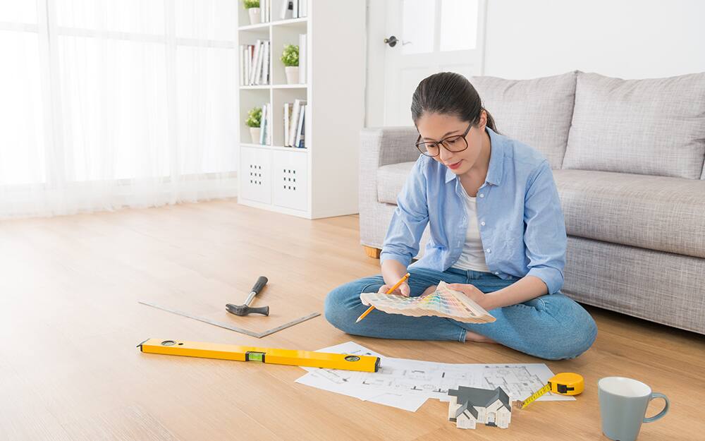 A woman sitting on the floor looking at a paint chip fan deck. A woman sitting on the floor looking at a paint chip fan deck.