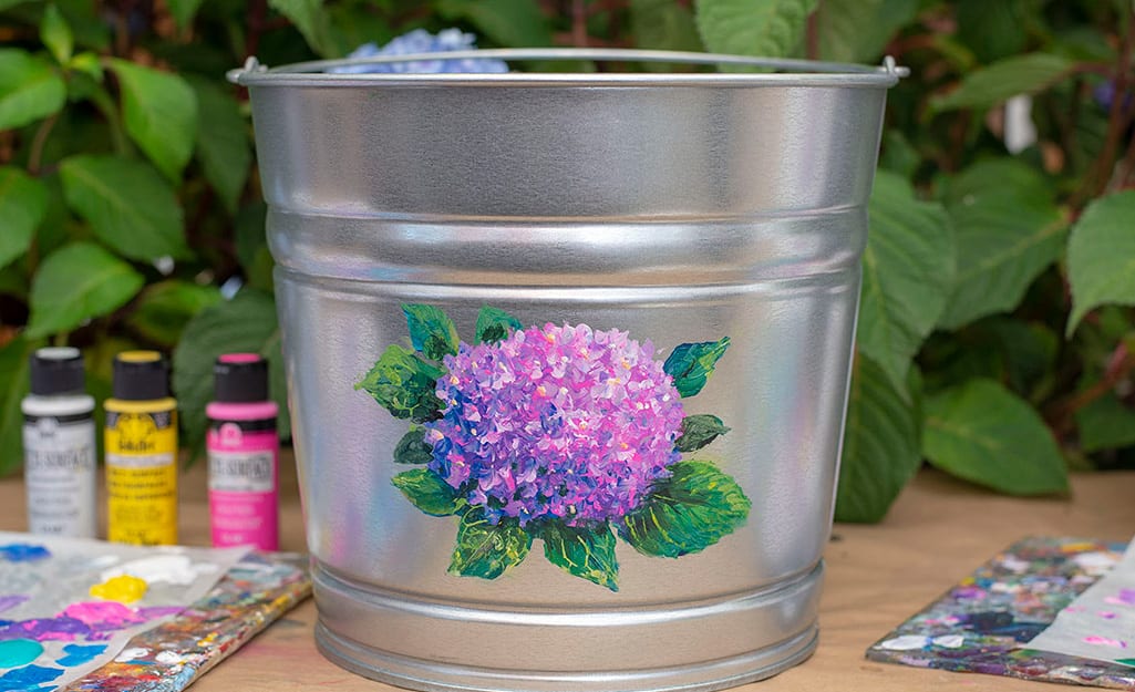 A galvanized bucket with a painted hydrangea on it. A galvanized bucket with a painted hydrangea on it.