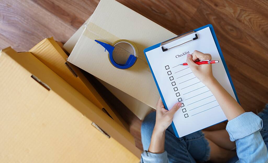 A woman makes a moving checklist. A woman makes a moving checklist.