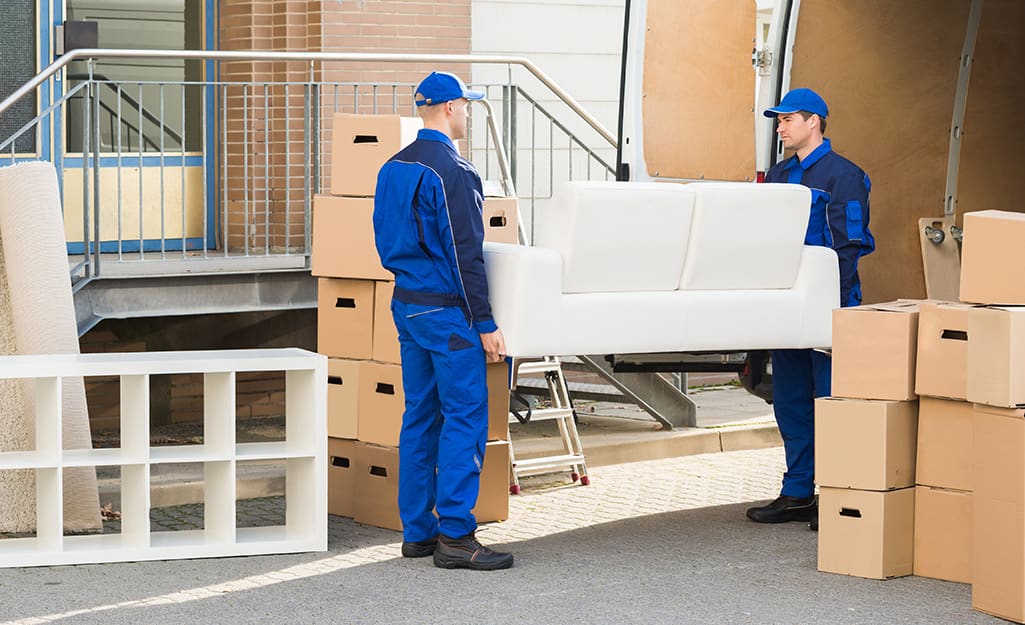 Professional movers load a sofa into a moving truck. Professional movers load a sofa into a moving truck.