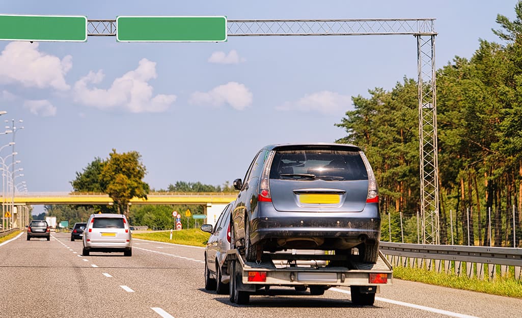 A vehicle being towed on a trailer along a highway. A vehicle being towed on a trailer along a highway.