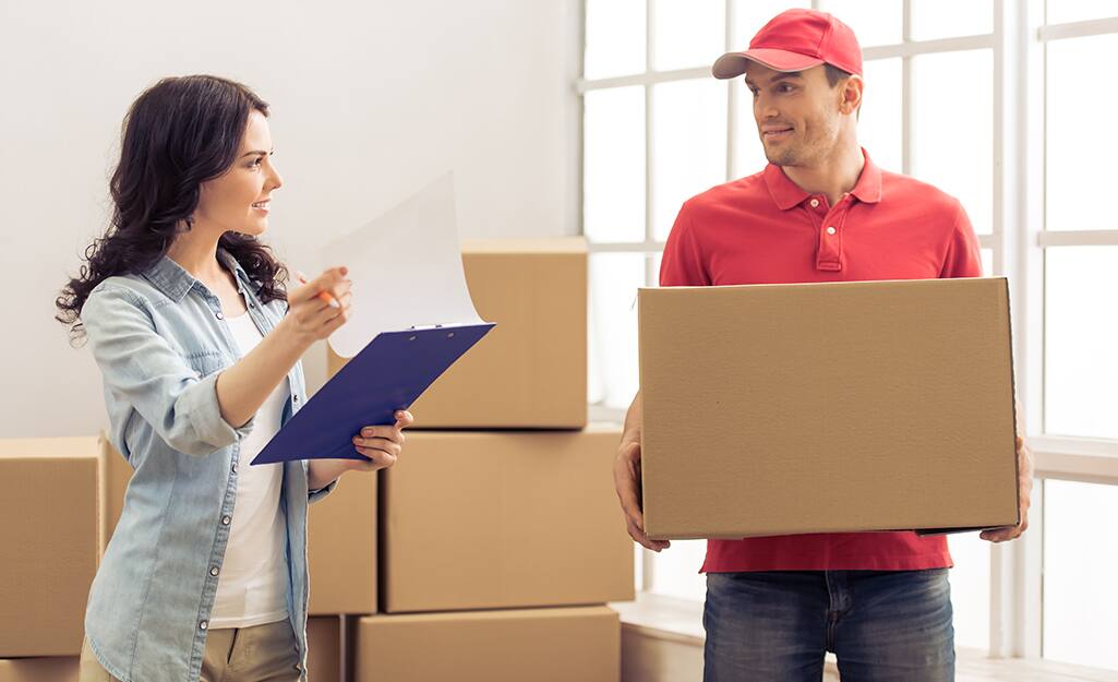 A woman with a notebook standing next to a man holding a box. A woman with a notebook standing next to a man holding a box.