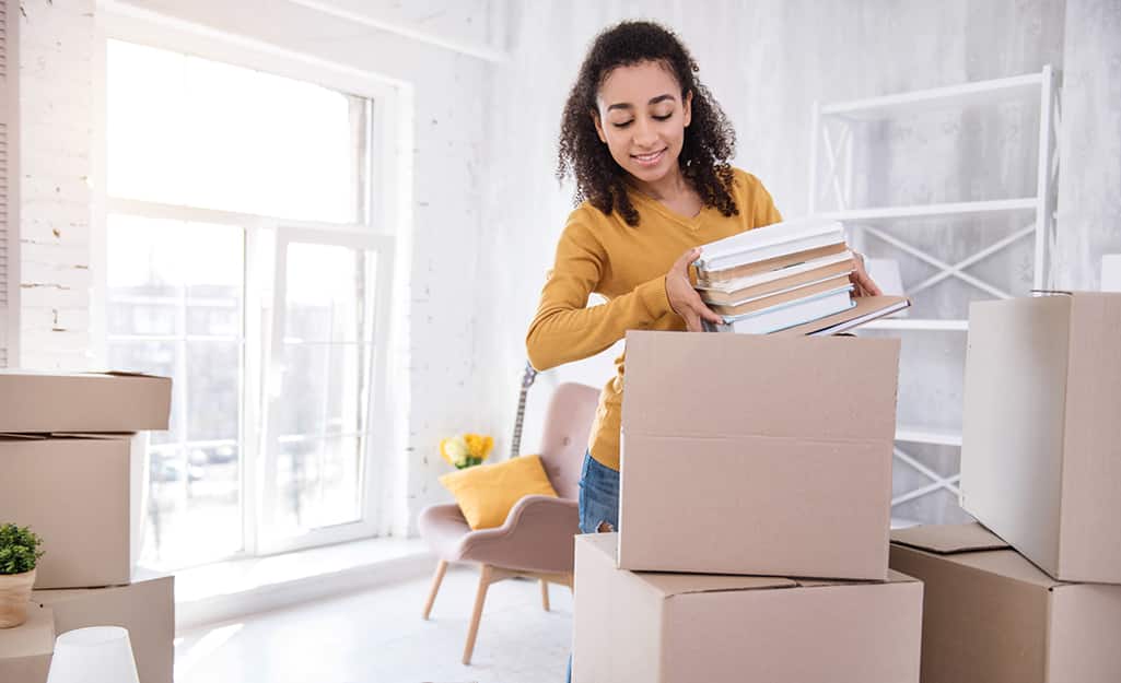 A young woman putting books into moving boxes. A young woman putting books into moving boxes.