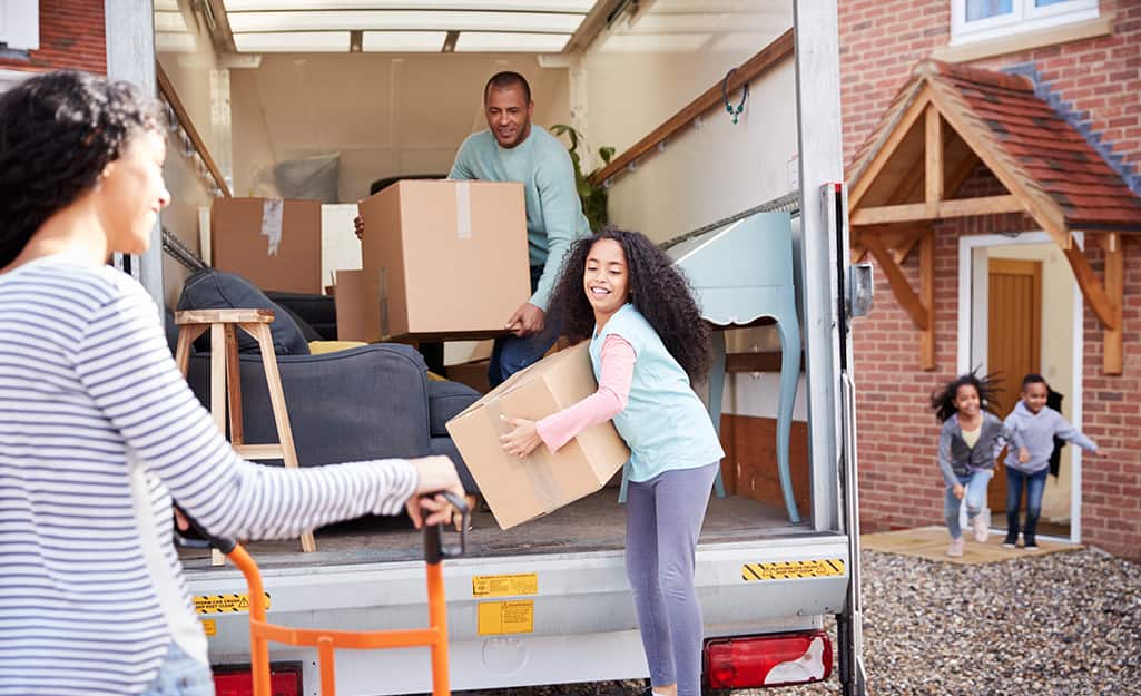 A group of people unloading a moving truck in front of a house. A group of people unloading a moving truck in front of a house.