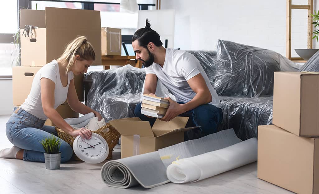 Two people unpacking boxes in a living space. Two people unpacking boxes in a living space.