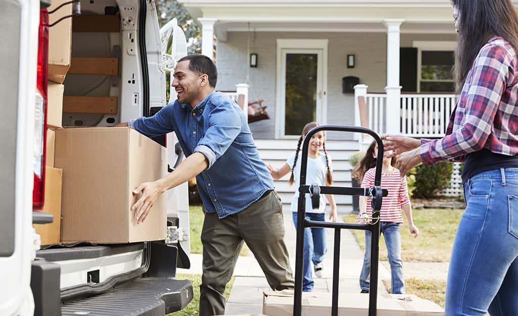Family loading boxes onto a moving truck. Family loading boxes onto a moving truck.