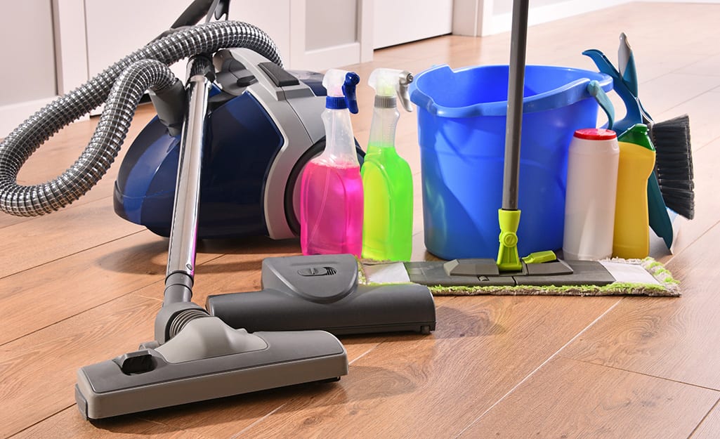 An assortment of cleaning supplies on a wood floor. An assortment of cleaning supplies on a wood floor.