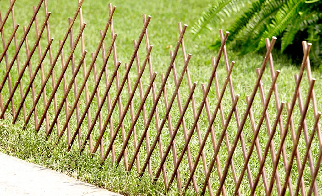An expandable privacy fence stretches along a lawn An expandable privacy fence stretches along a lawn