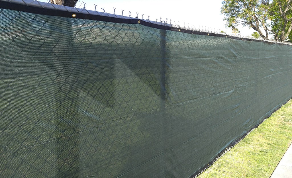 A green mesh privacy screen covers a chain link fence A green mesh privacy screen covers a chain link fence