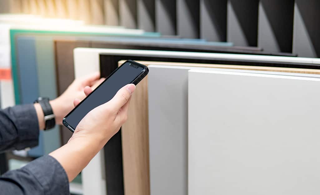 Person holds smartphone while comparing different slabs of quartz countertops. Person holds smartphone while comparing different slabs of quartz countertops.