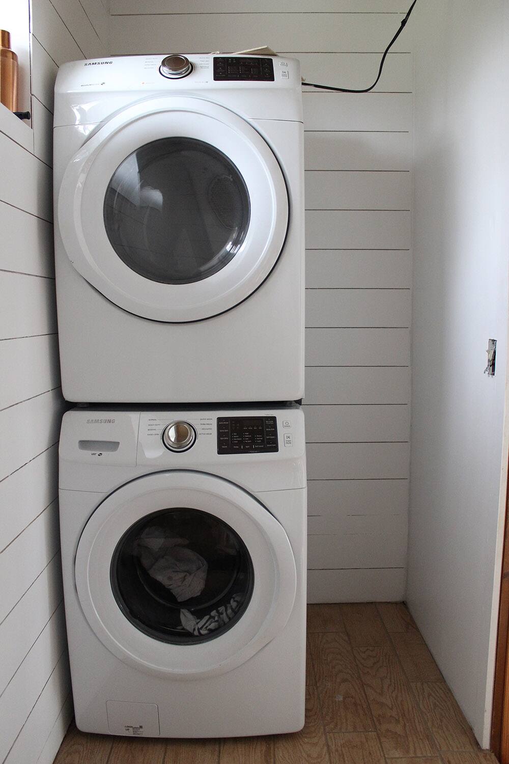 A room with white plank walls and washer and dryer. 