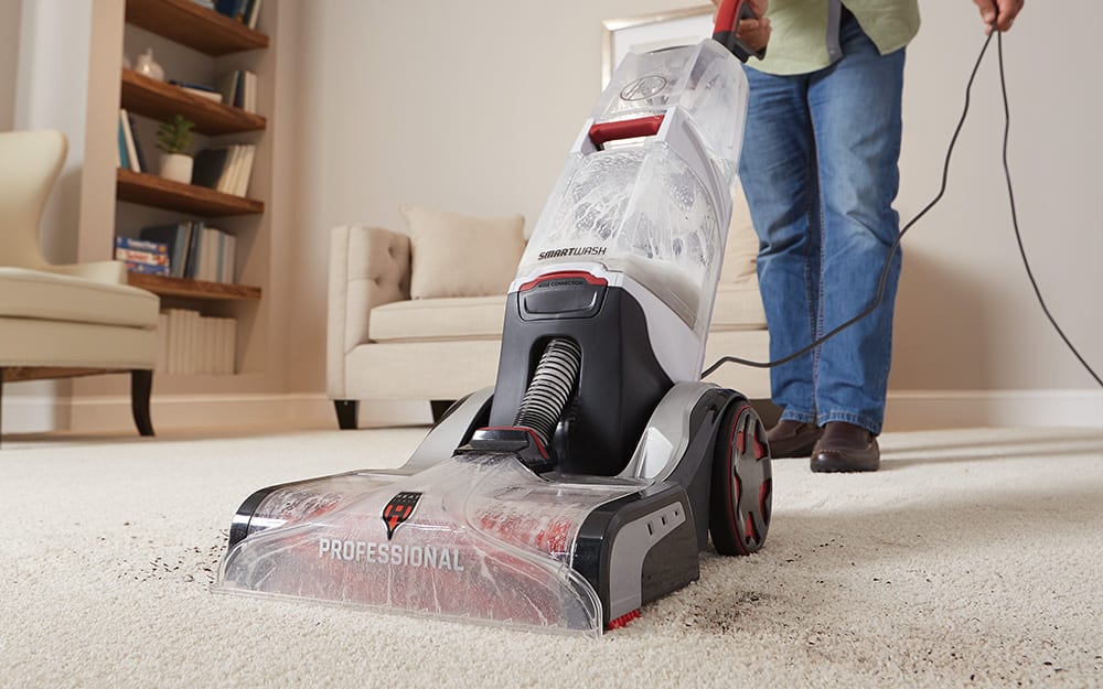 A person using a carpet cleaner to clean a carpet A person using a carpet cleaner to clean a carpet