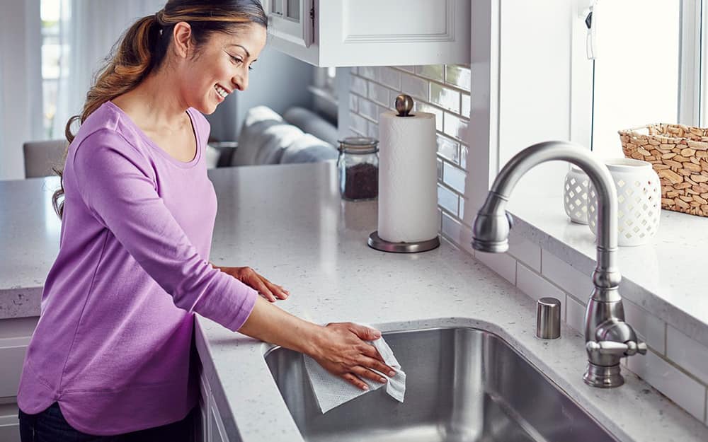 Woman cleaning a kitchen sink with a cloth Woman cleaning a kitchen sink with a cloth