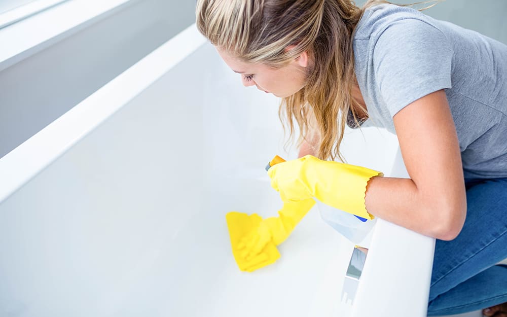 Woman wearing rubber gloves and cleaning a bathtub Woman wearing rubber gloves and cleaning a bathtub