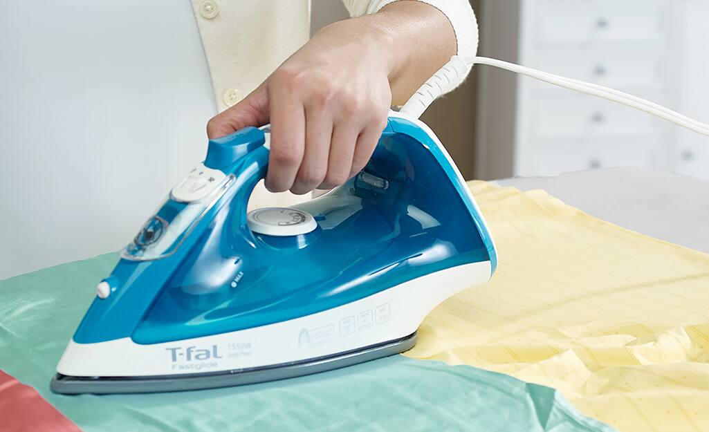 A woman ironing a shirt on an ironing board. A woman ironing a shirt on an ironing board.