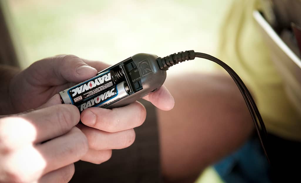 A person inserts a pair of general purpose batteries into a device. A person inserts a pair of general purpose batteries into a device.