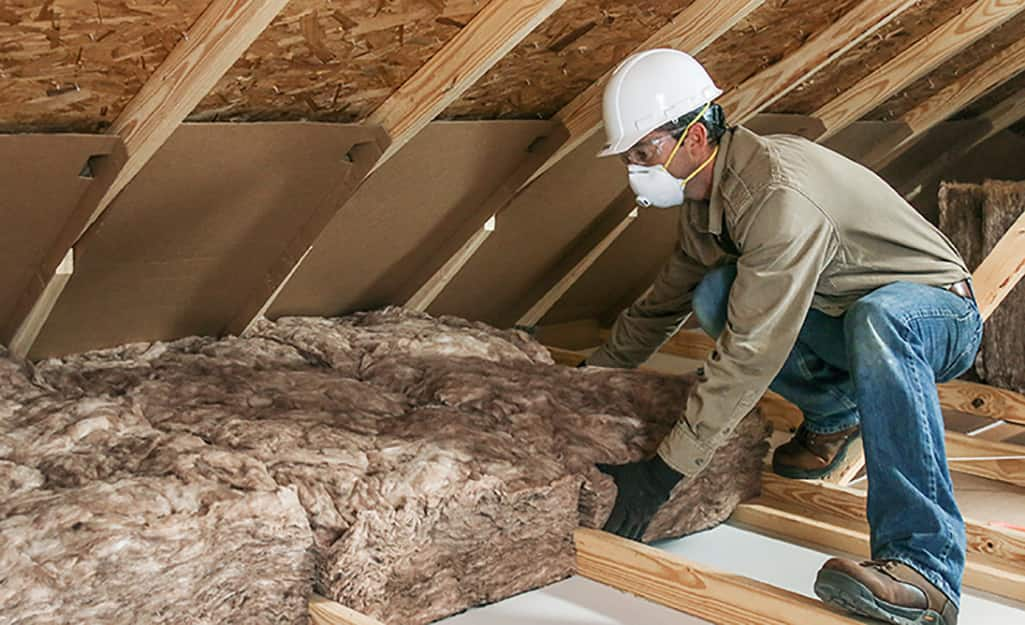 A person putting in insulation in an attic.