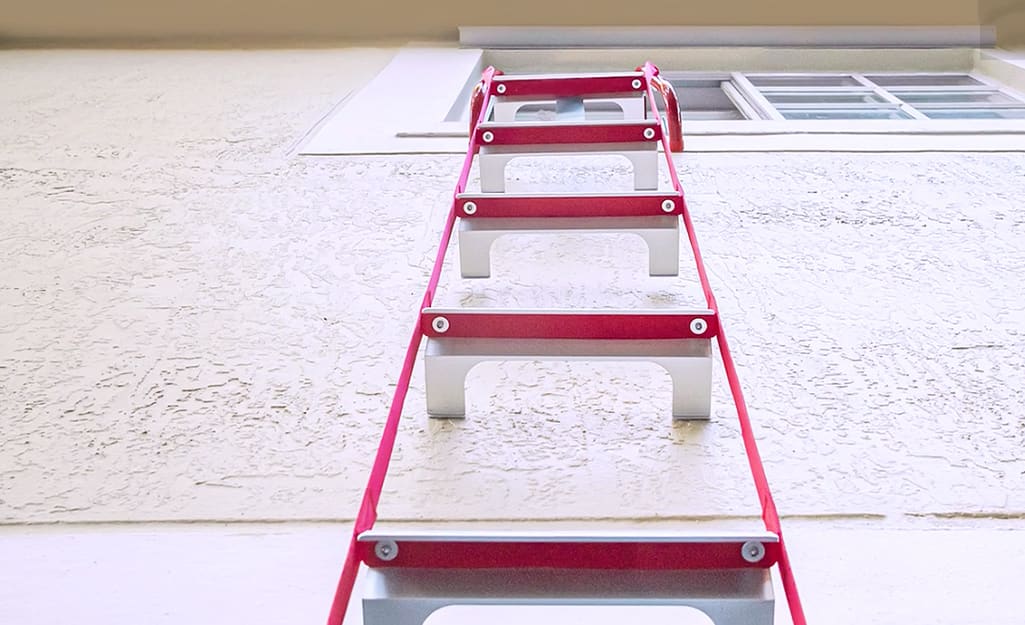 A fire escape ladder hanging from a second story window. A fire escape ladder hanging from a second story window.