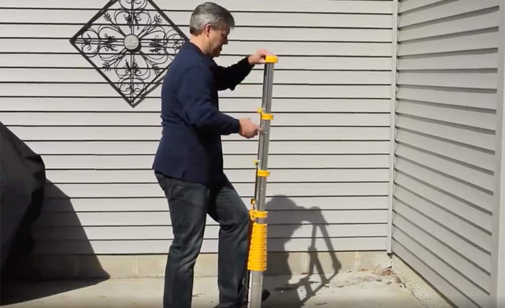 A man extending a telescoping ladder. A man extending a telescoping ladder.