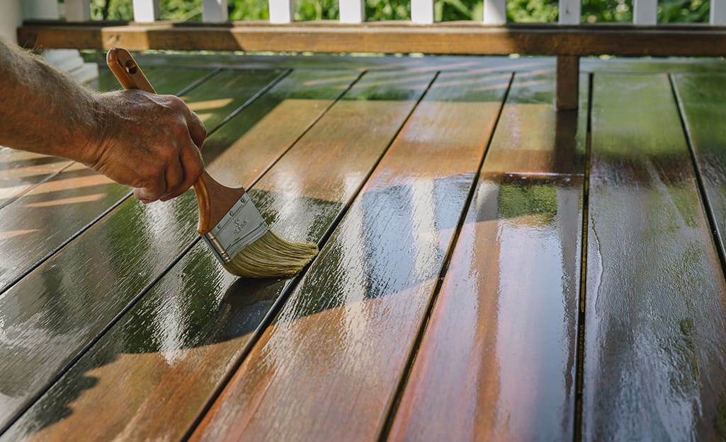Person applying sealer to a wood deck. Person applying sealer to a wood deck.