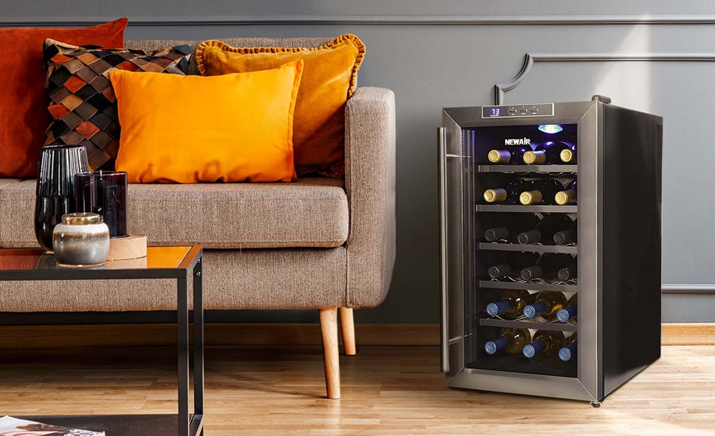 A free standing wine cooler sits near a sofa. A free standing wine cooler sits near a sofa.
