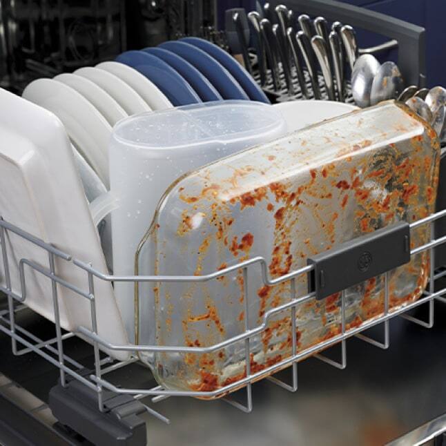 Dirty dishes are all neatly stacked into the dishwasher's lower drawer, ready to clean.