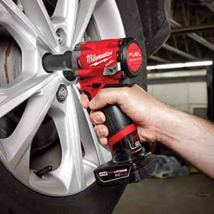 A man removing lug nuts from a car tire with the M12 FUEL Stubby Impact Wrench.